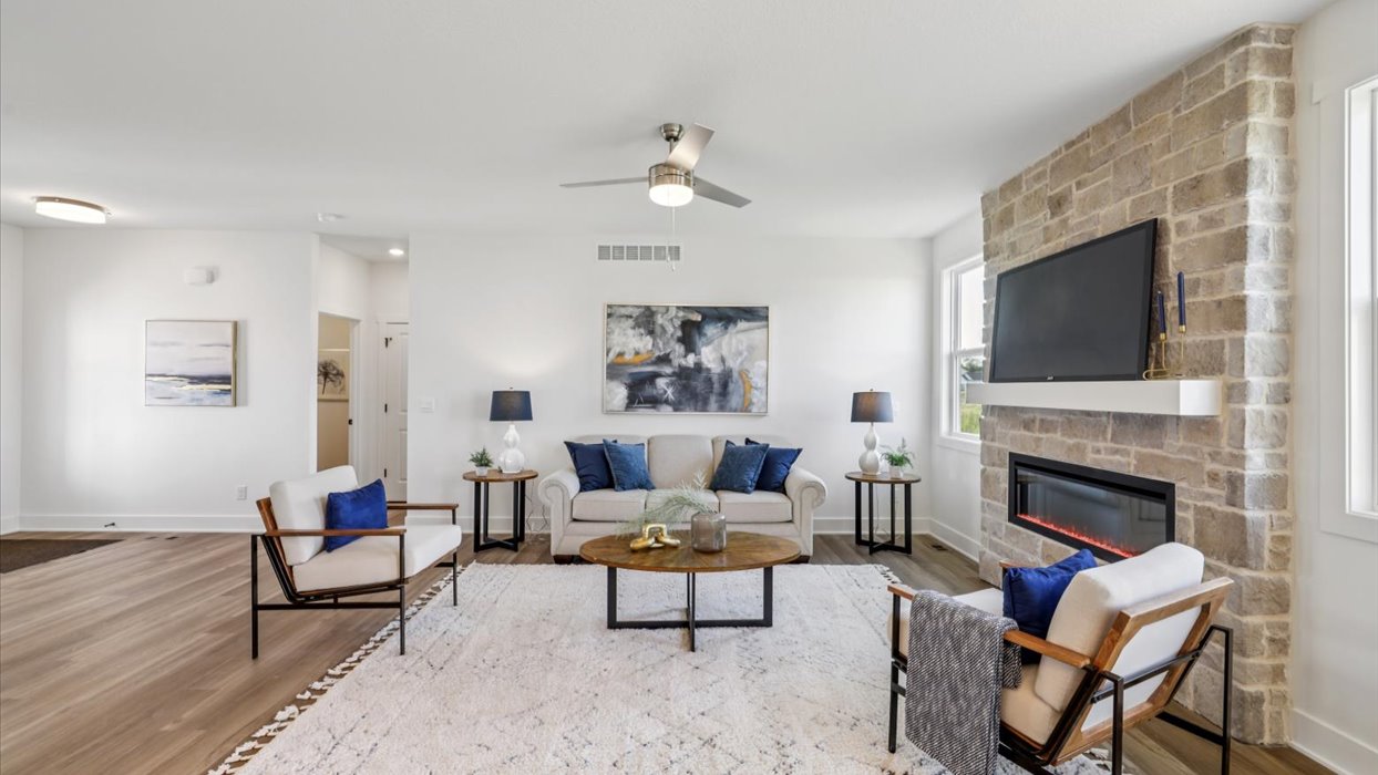 bright living room with stone fireplace and ceiling fan