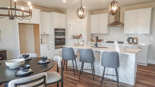 white kitchen with island and quartz countertops and pendant lighting