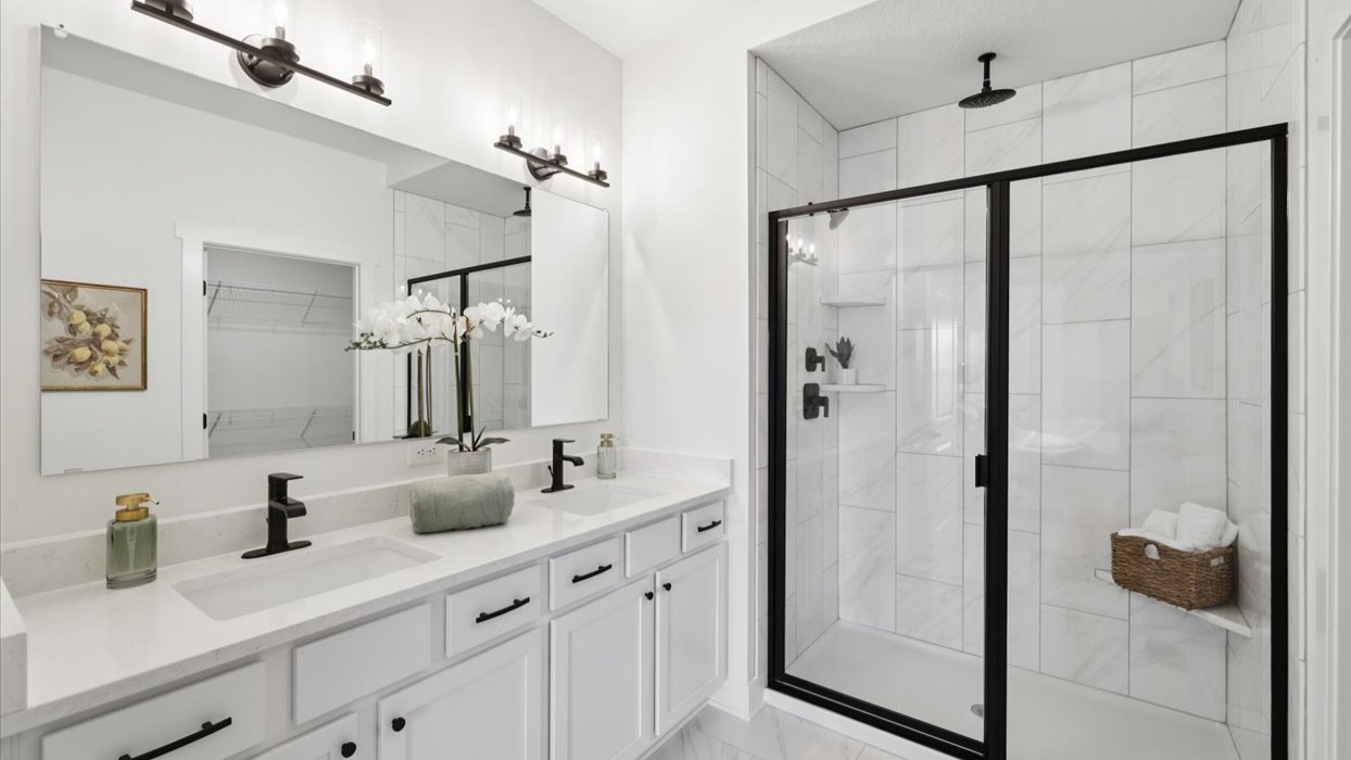 primary bedroom with large mirror and dual sinks