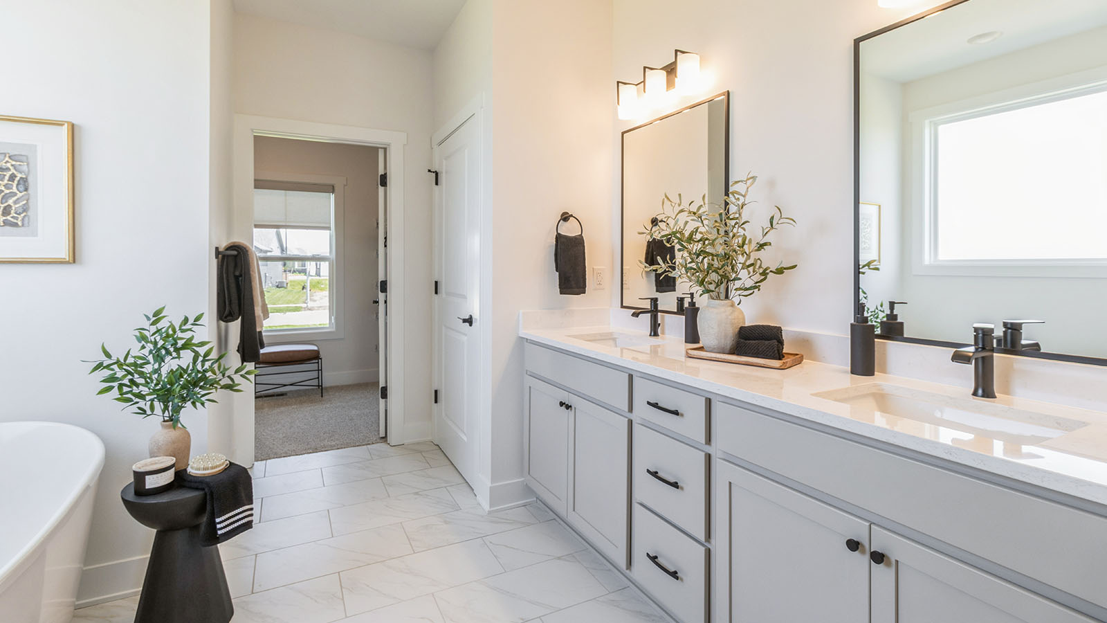 spacious lincoln primary bathroom with two mirrors and tan cabinets