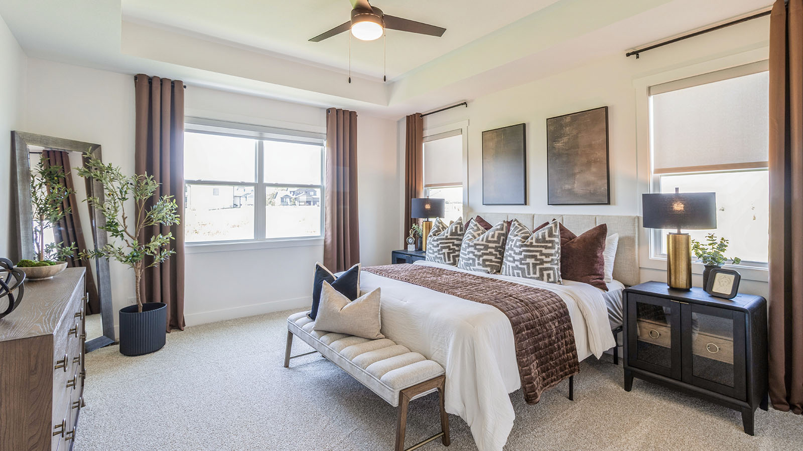 Large primary bedroom with lots of windows and tray ceilings with white ved