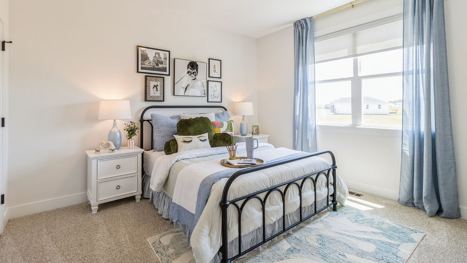 Second bedroom with large window and queen bed with white wood nightstands