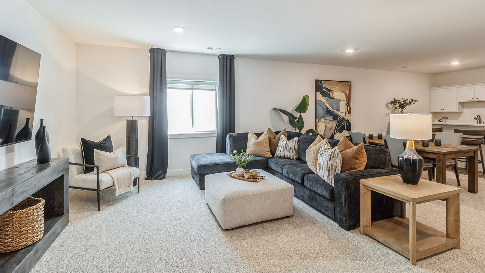 Spacious finished basement with dark couch and mounted tv with tv stand