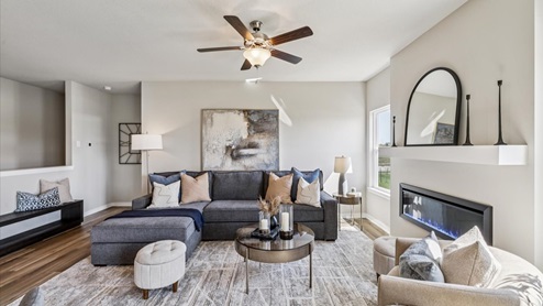 bright living room with electric fireplace and ceiling fan and windows
