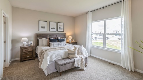 primary bedroom with large window and seating area at end of the bed