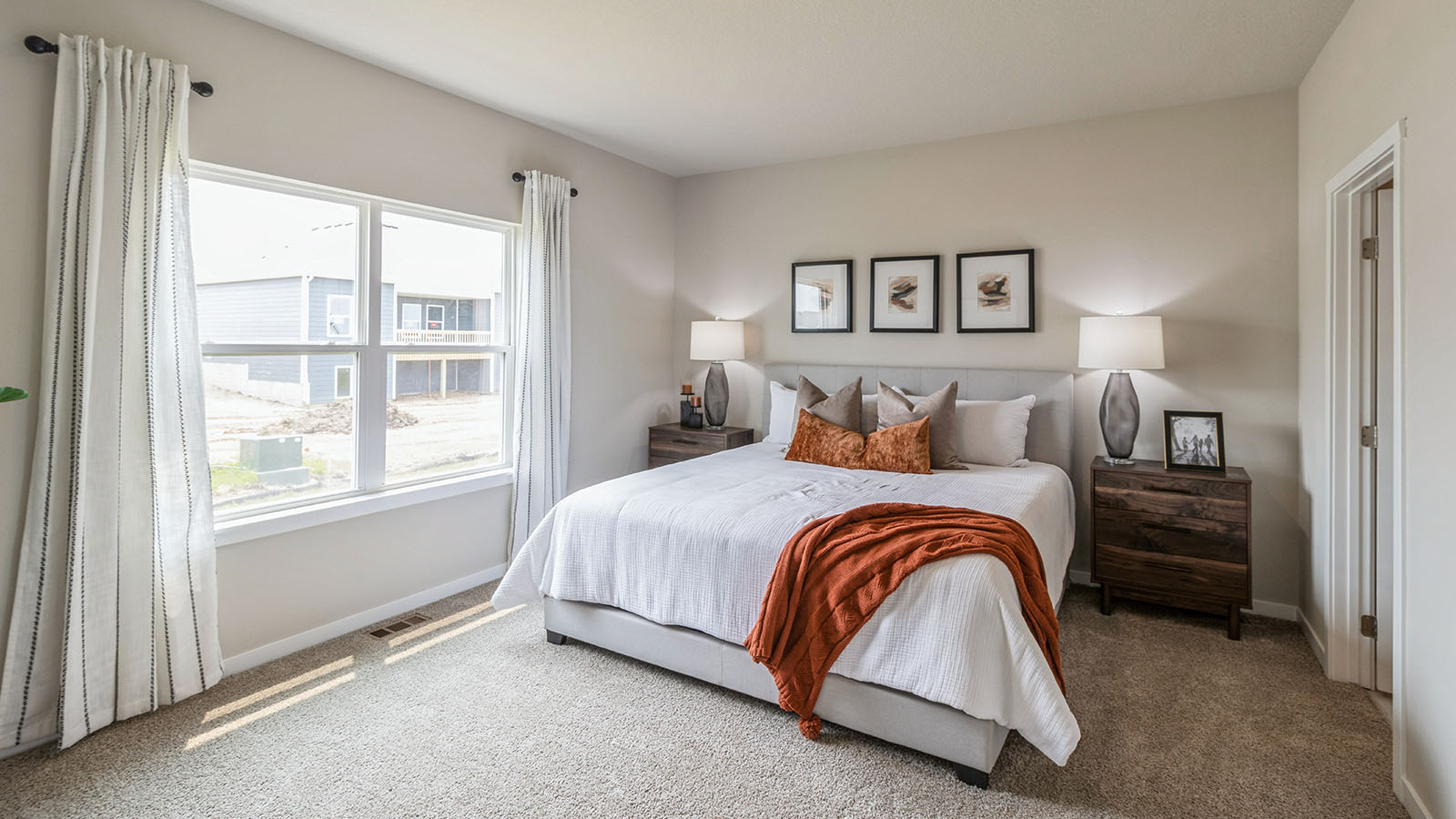 primary bedroom with large white bed and two wood nightstands