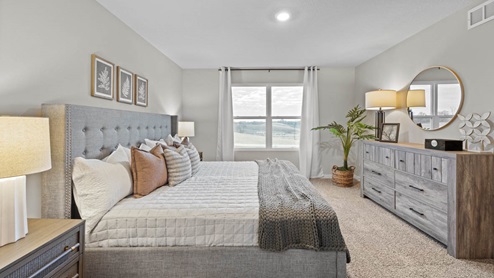 Large primary bedroom with king bed and grey dresser