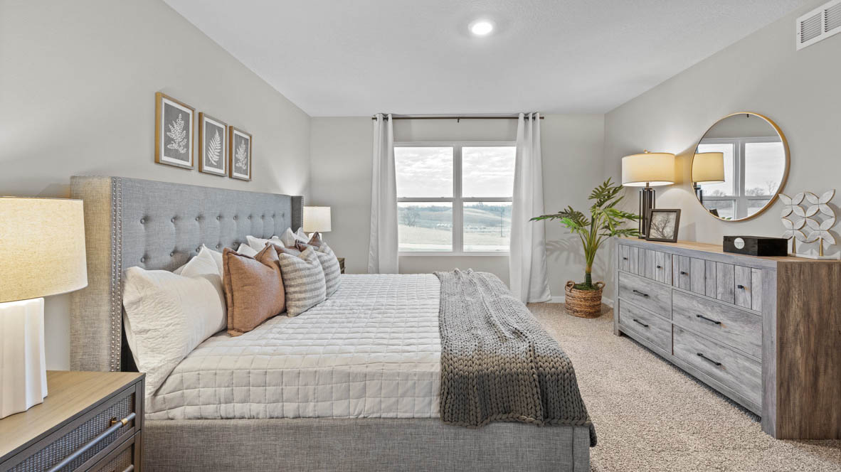 Large primary bedroom with king bed and grey dresser