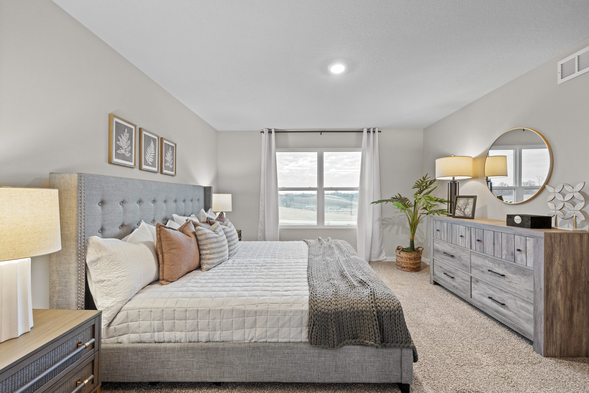 Large primary bedroom with king bed and grey dresser