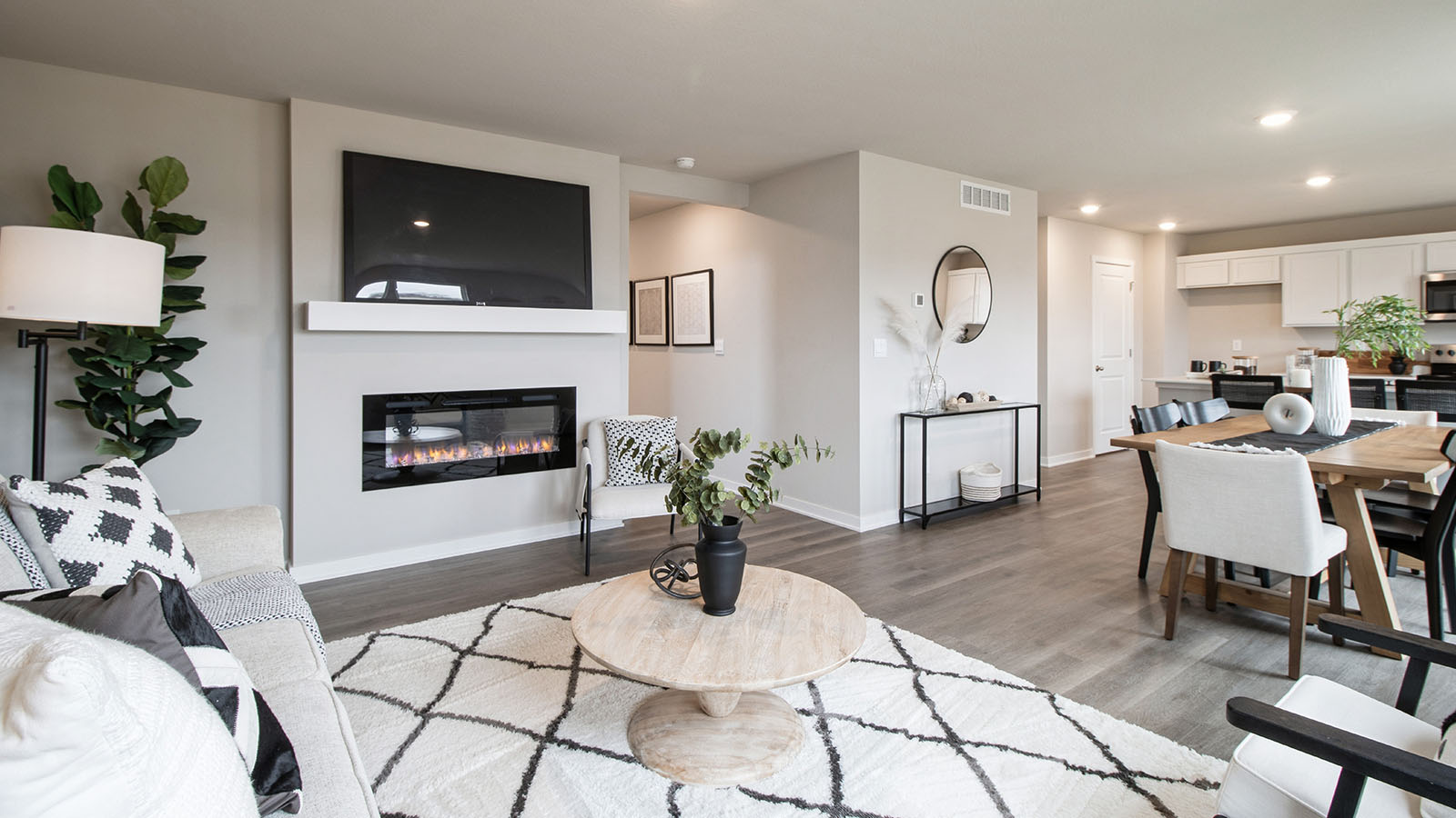 Open concept living room with electric fireplace overlooking dining area and kitchen