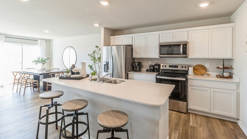 Bright white kitchen with island and quartz countertops and stainless-steel appliances