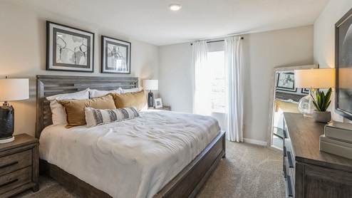 Large Roland primary bedroom with white bed and wood nightstands and dresser