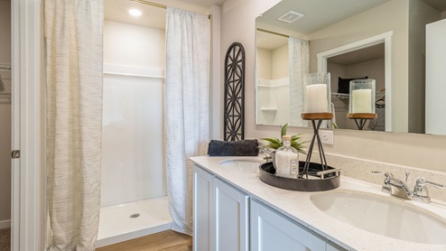 Primary bathroom with large mirror and dual sinks with walk-in shower