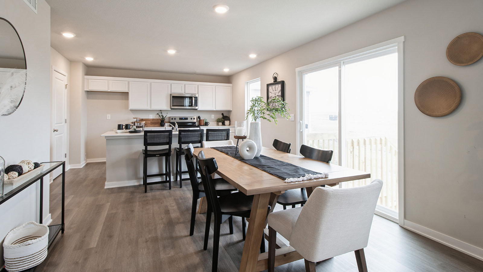 Open concept dining area with wood table and black chairs next to kitchen