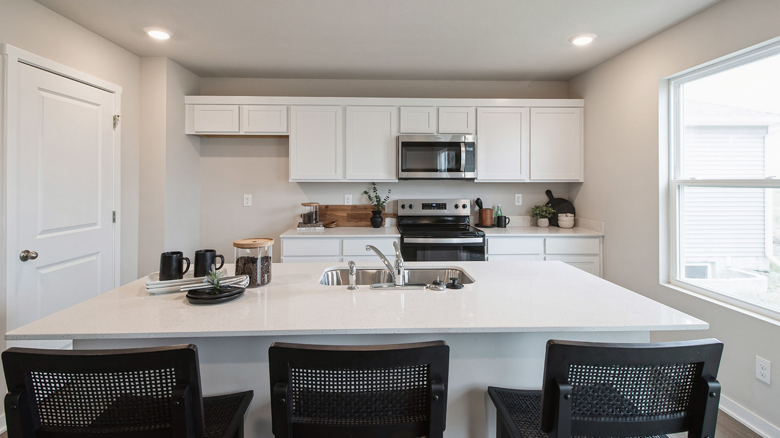 Close up view of modern kitchen with island and black barstools