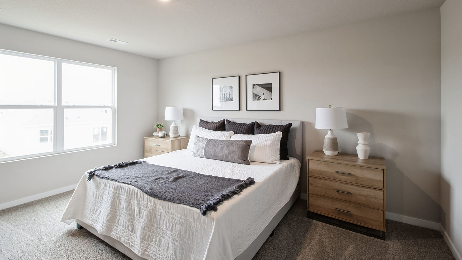Spacious primary bedroom with white bed and wood nightstands