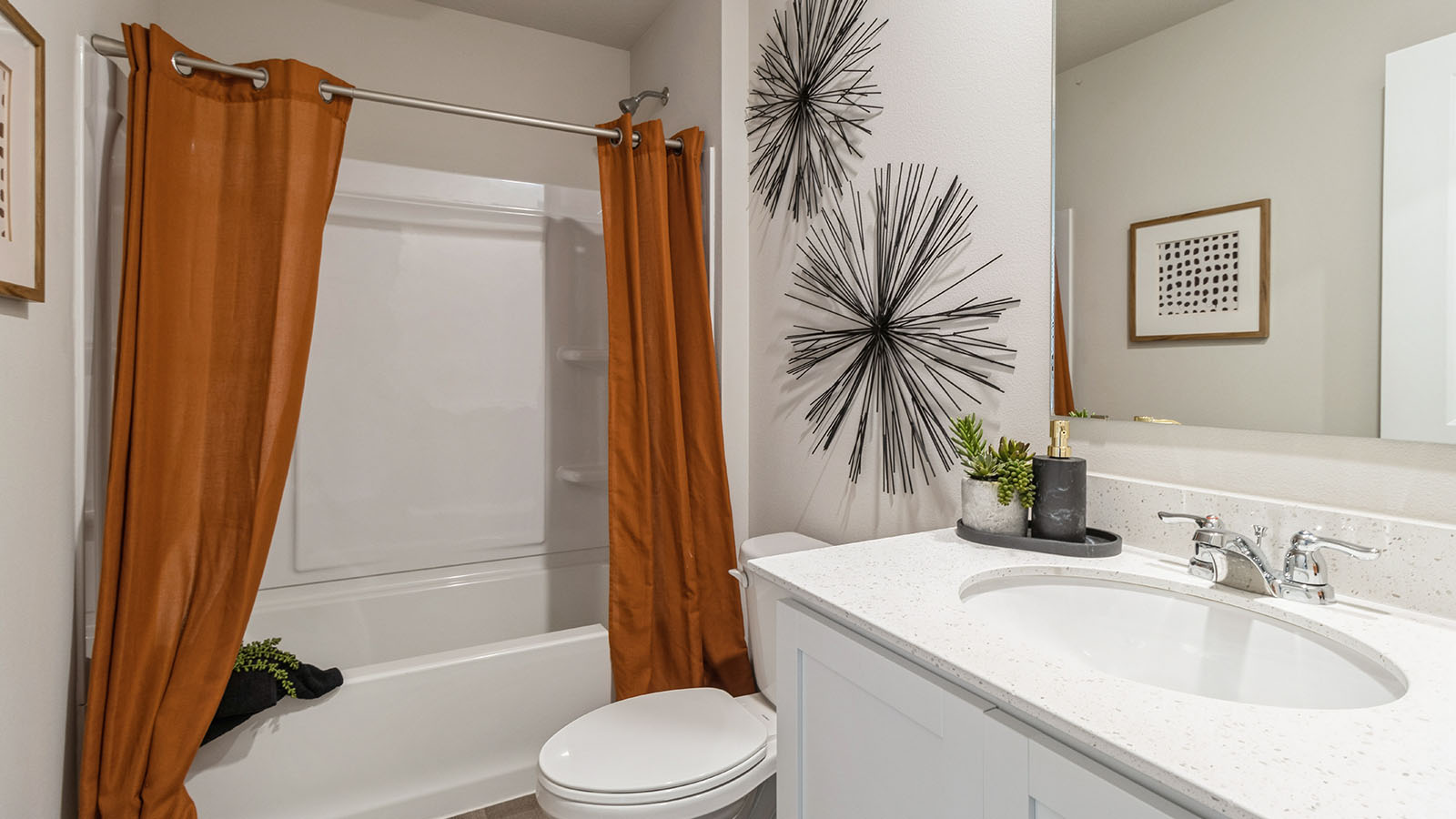 First bathroom with sink and bathtub and orange shower curtains