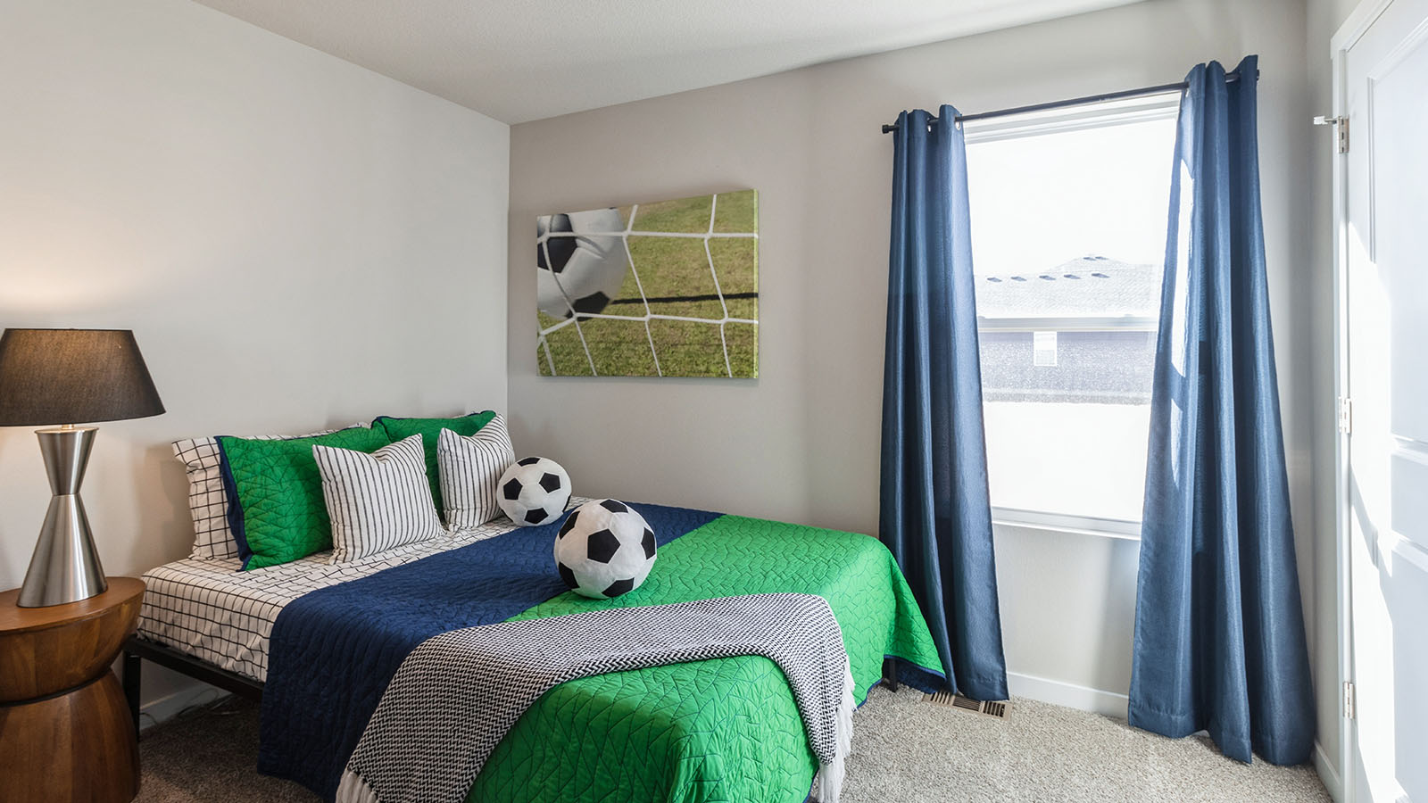 Second bedroom with green bed and soccer ball pillows and small window