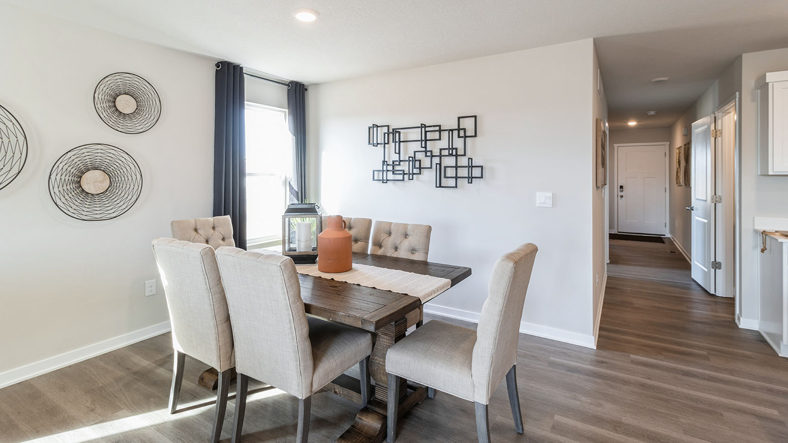 Dining area with wood table and white chairs next to small window