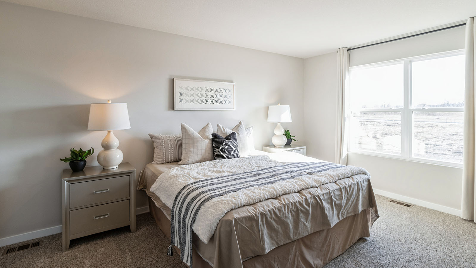 Primary bedroom with large neutral bed and large window