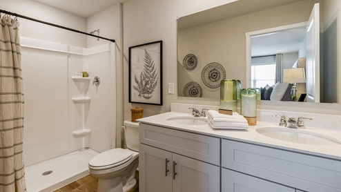 Large primary bathroom with dual sinks and large mirror with white cabinetry