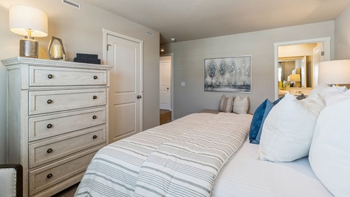 Primary bedroom with white bed and dresser with view of primary bathroom