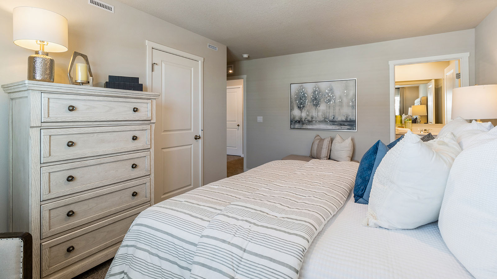 Primary bedroom with white bed and dresser with a view of the primary bathroom