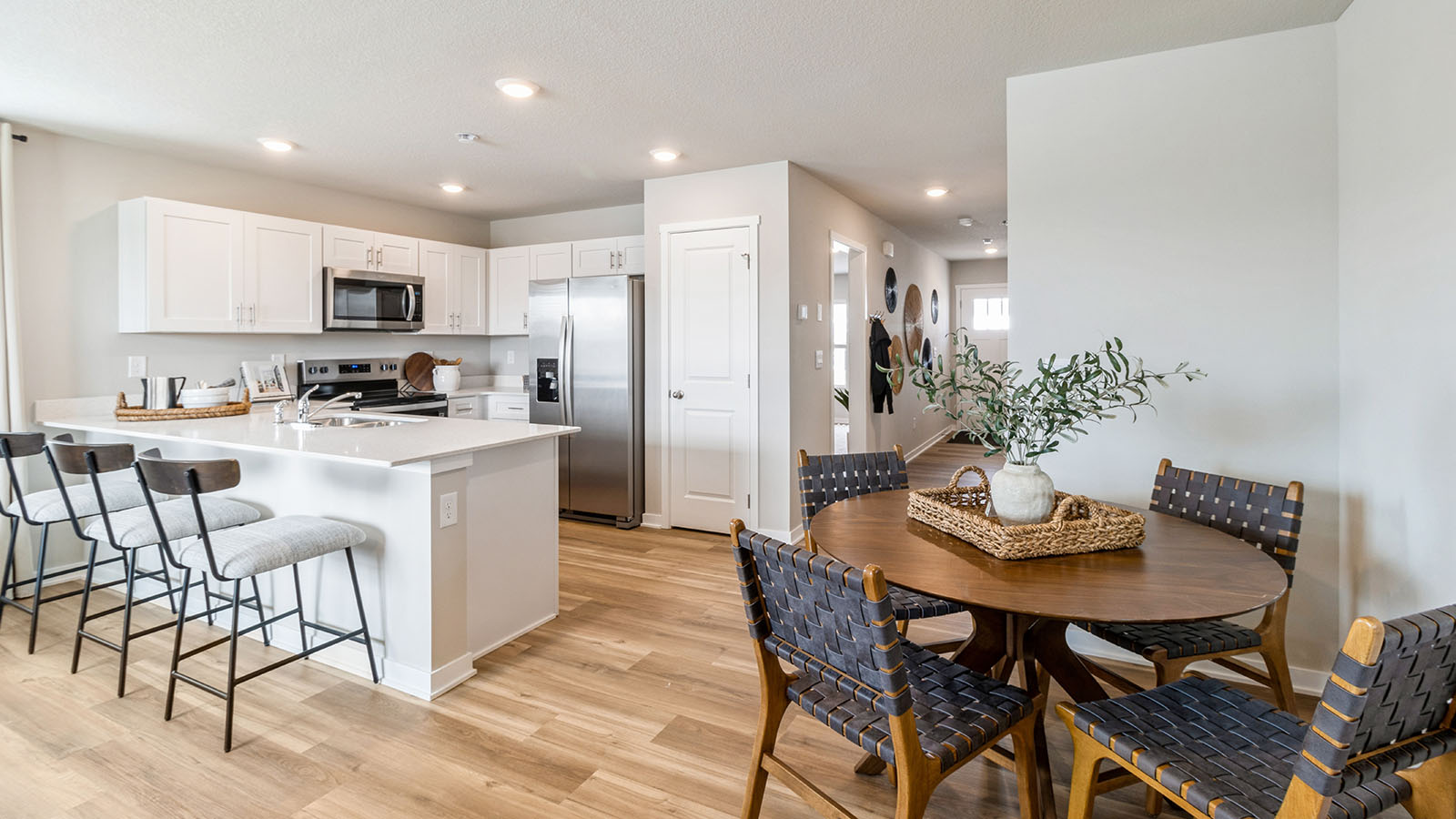 Dining area with wooden table and black chairs next to a white kitchen