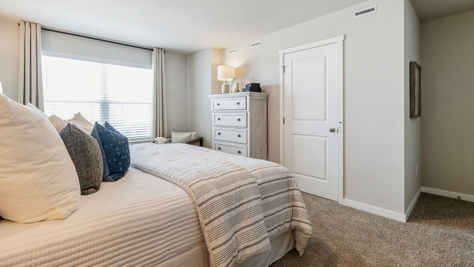 Pearson primary bedroom with tan bed and white dresser with closet