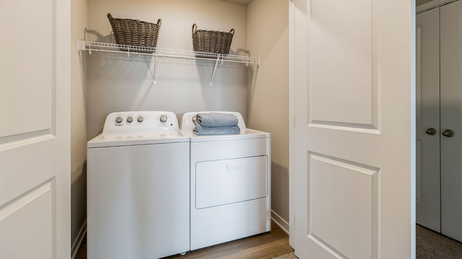 Closet with washer and dryer with white shelving above