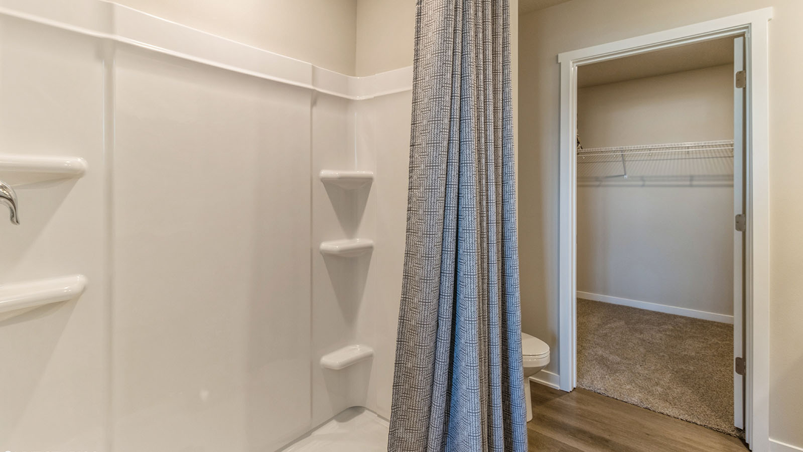 Shower in primary bathroom with view of walk-in closet
