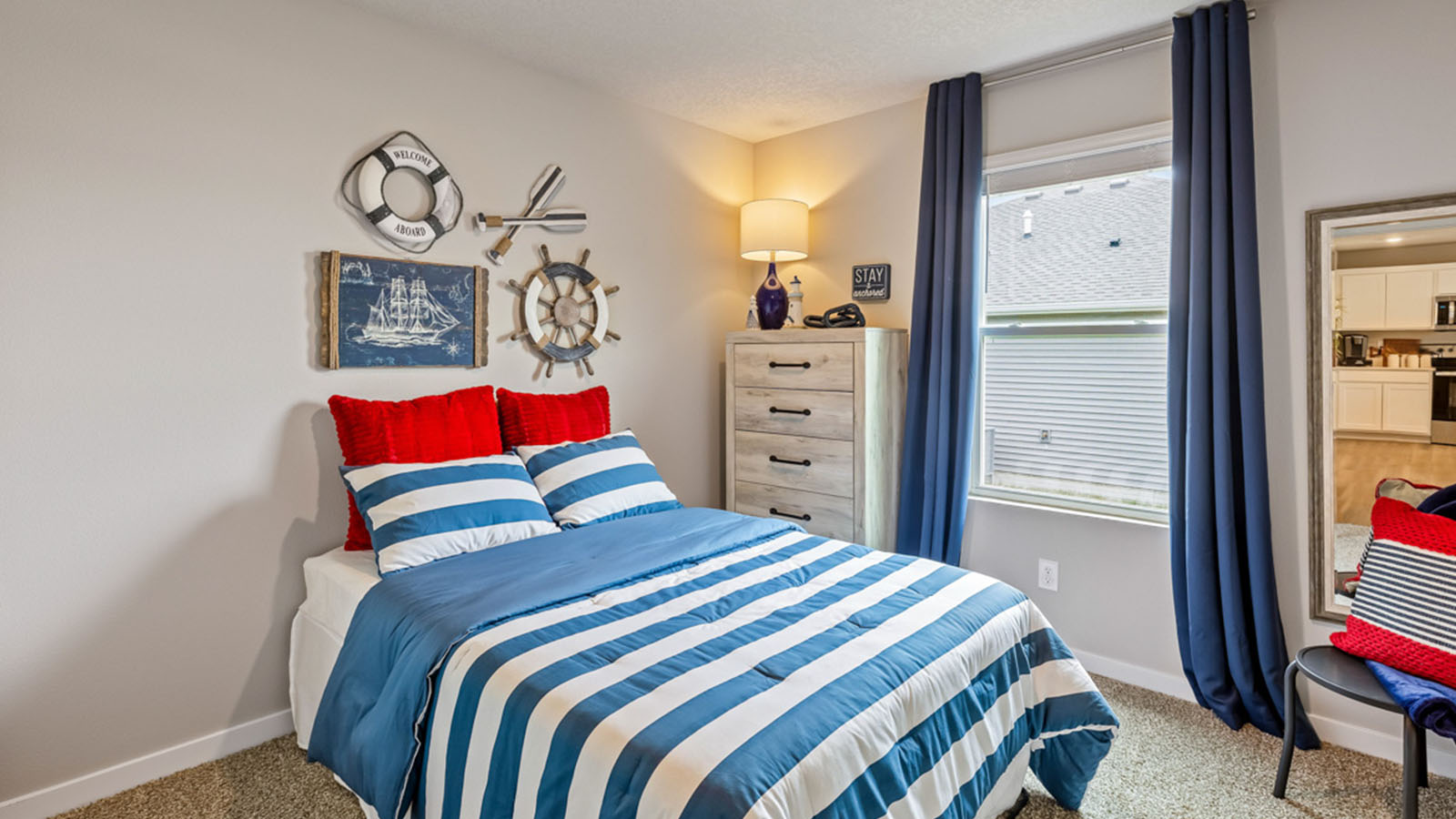 Second bedroom with blue striped bed and white dresser
