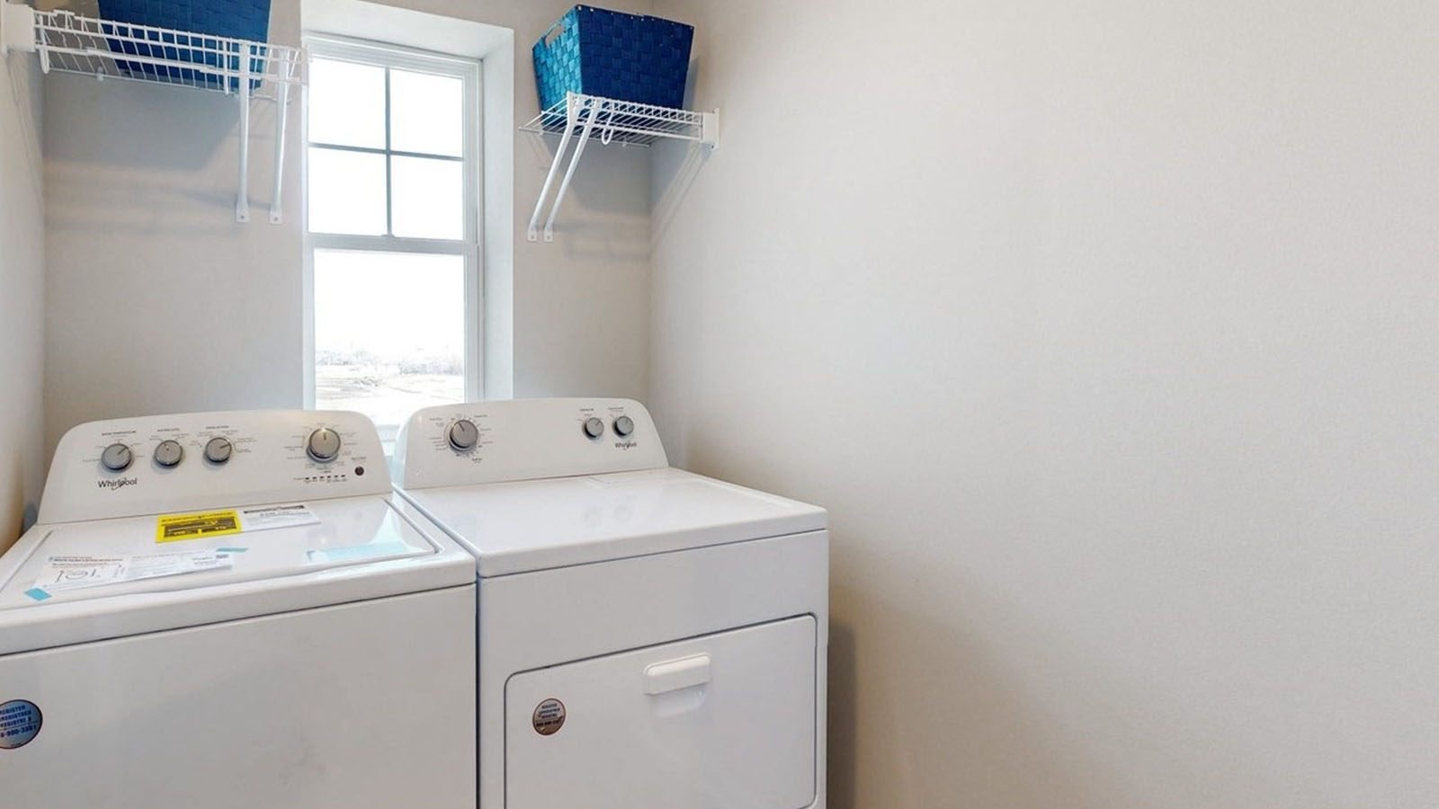 New construction laundry room at Painted Woods West Townhomes includes overhead storage and modern finishes