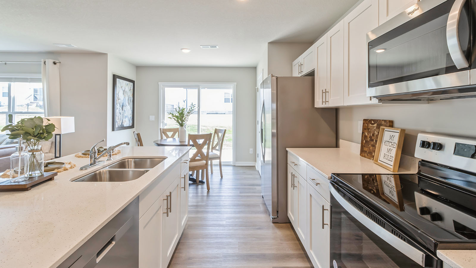 Kitchen and family room combination with hard surface countertops and stairway access in Painted Woods West Townhomes