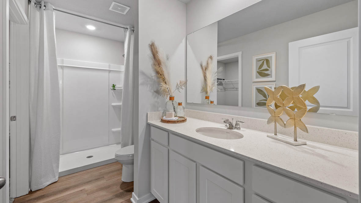 First bathroom with large mirror and white cabinets