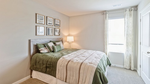 First bedroom with small window and large green bed