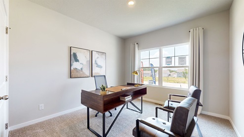 First bedroom staged as an office with brown desk and chairs