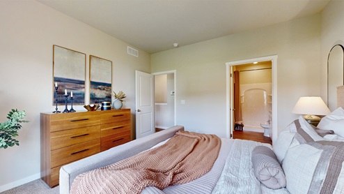 Primary bedroom with brown dresser and two portraits on wall