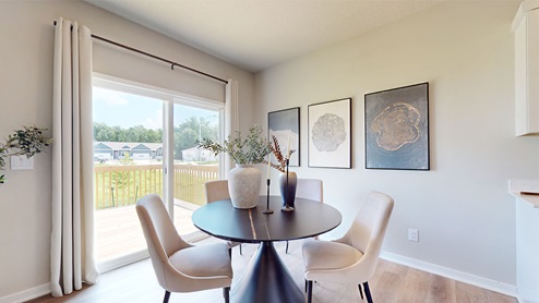 Dining area with black table and white chairs next to sliding glass doors