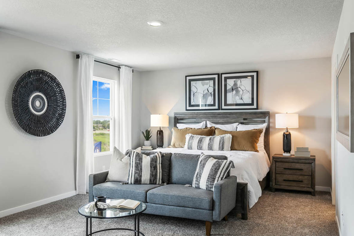 Carpeted primary bedroom on the second level with space for a bed and a cozy sitting area.