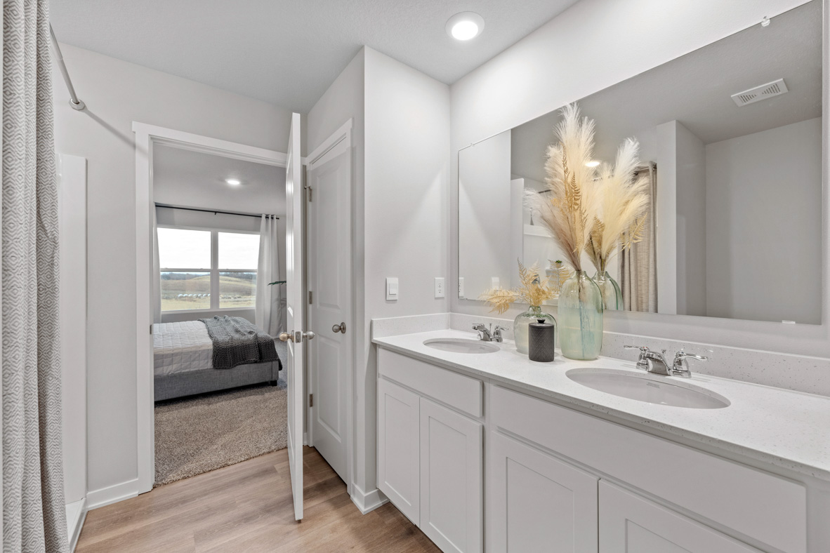 Primary bathroom with a linen closet and double vanity with white, shaker-style cabinets.