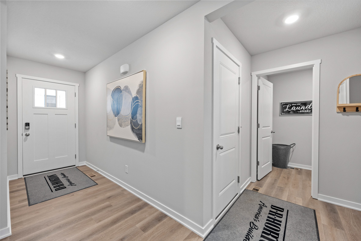 View from the hallway of the front door and door leading into the laundry room in the Harmony plan.