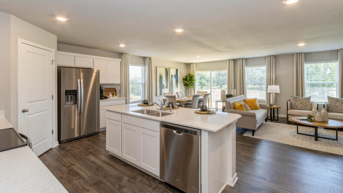Center island in the Neuville's kitchen with an undermounted split sink, built in stainless-steel dishwasher, and countertop seating space for three.