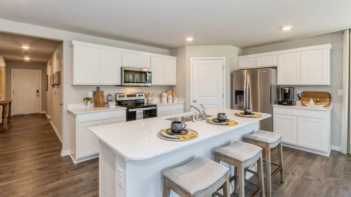 Neuville-plan kitchen with white, shaker-style cabinets, stainless-steel appliances, a center island, an corner pantry.