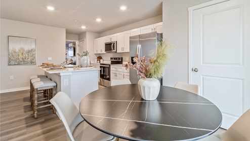 Black round dining table overlooking modern kitchen