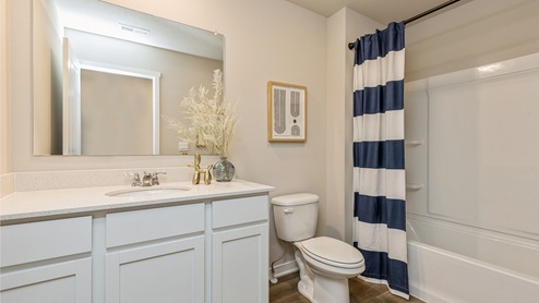 First bathroom with white cabinetry and bathtub