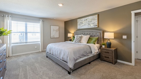 Spacious primary bedroom with large window and grey bed