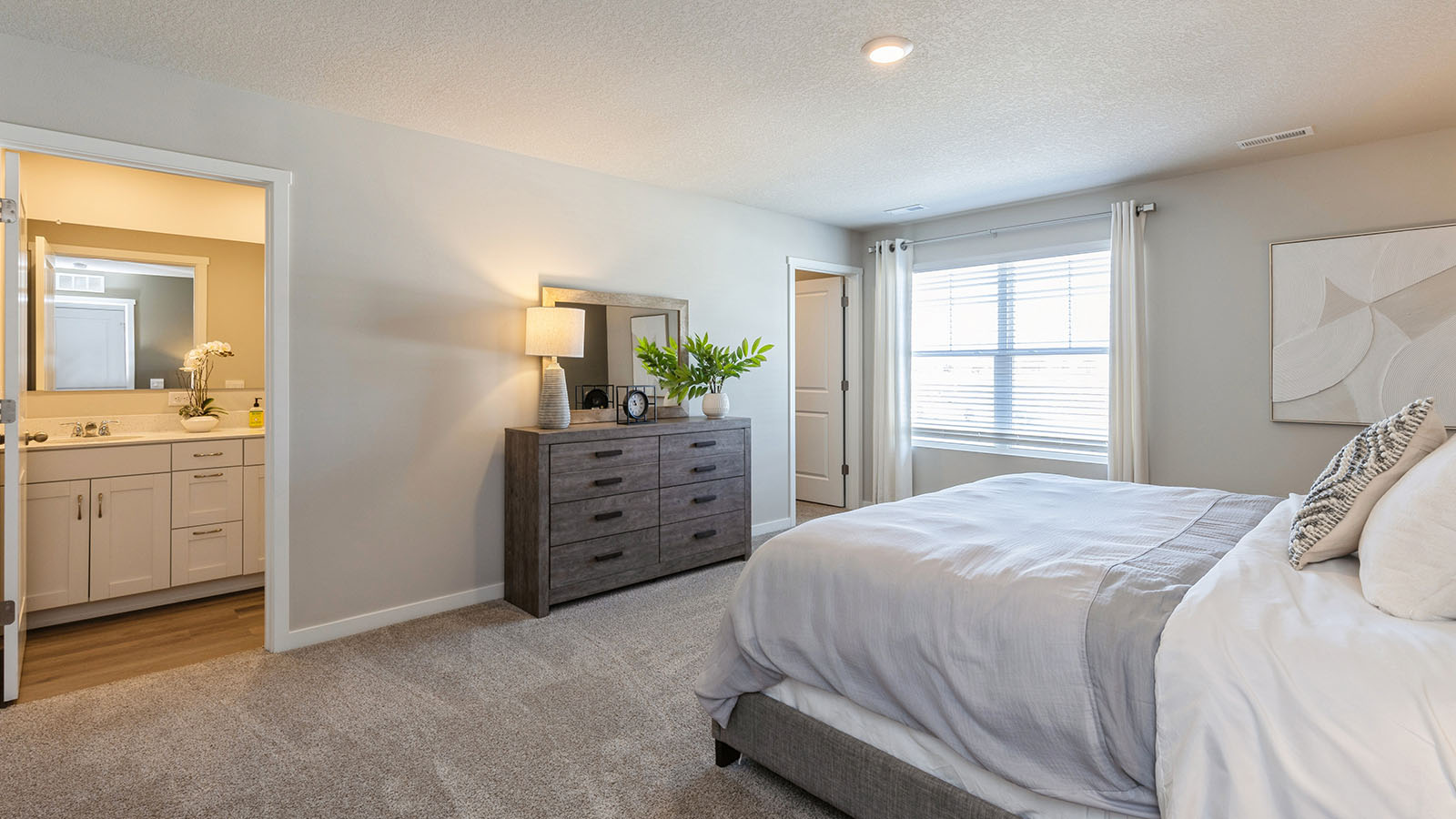 Primary bedroom with large window and overhead lighting