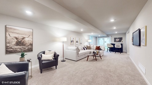 Finished basement with overhead lighting and seating