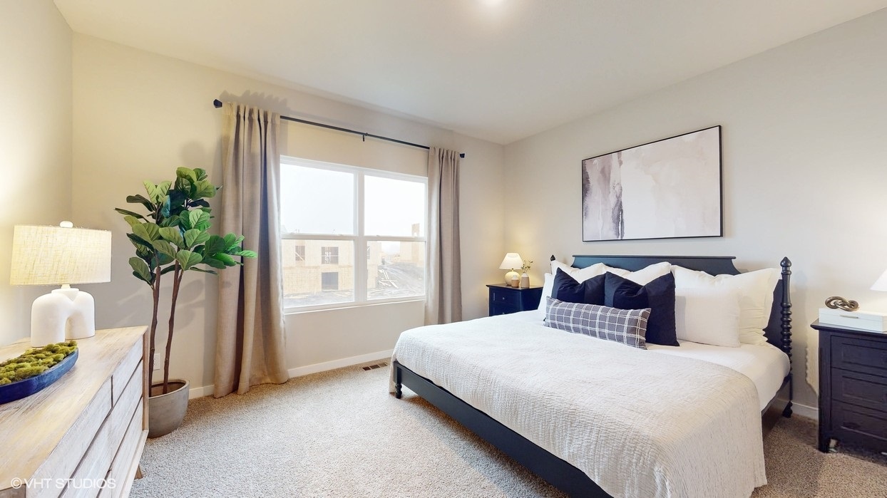 Primary bedroom with large white bed and white dresser